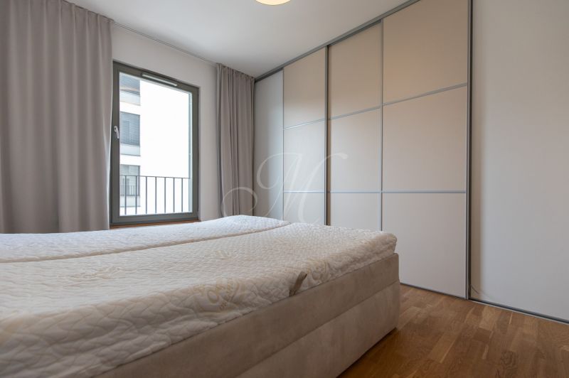 A bedroom with a large window, a built-in wardrobe, and a bed in a 3-room apartment.