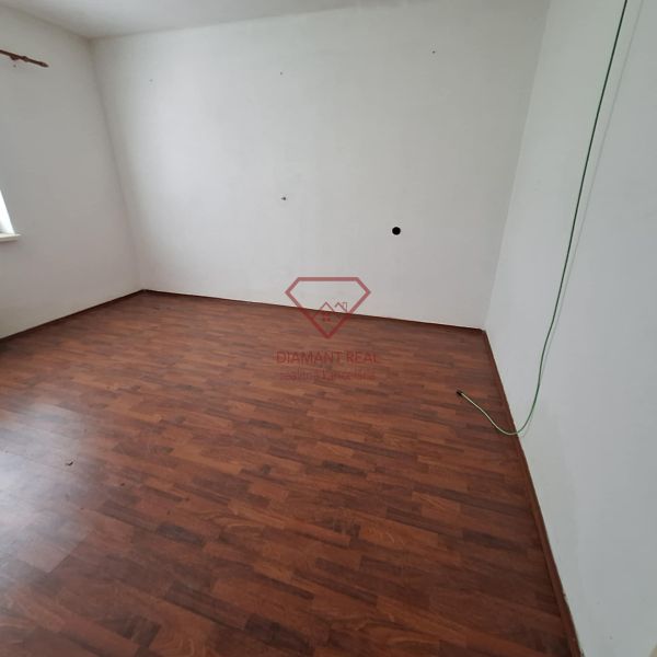 An empty room with laminate flooring and white walls in a family house.