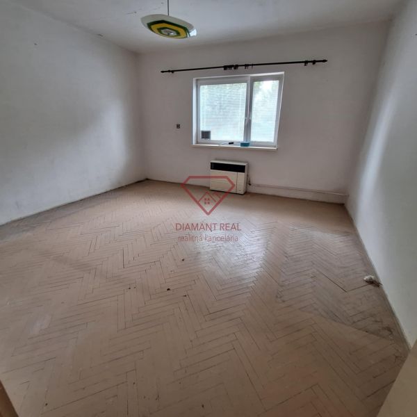 An empty room with parquet flooring and a window in a family house, basic design without furniture.
