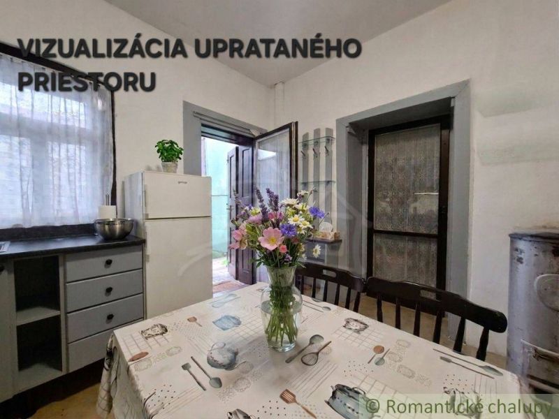 Dining room in a family house with flowers on the table and a white refrigerator.