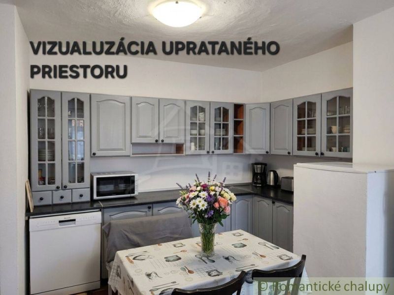 A kitchen in a family house with gray cabinets and flowers on the table.