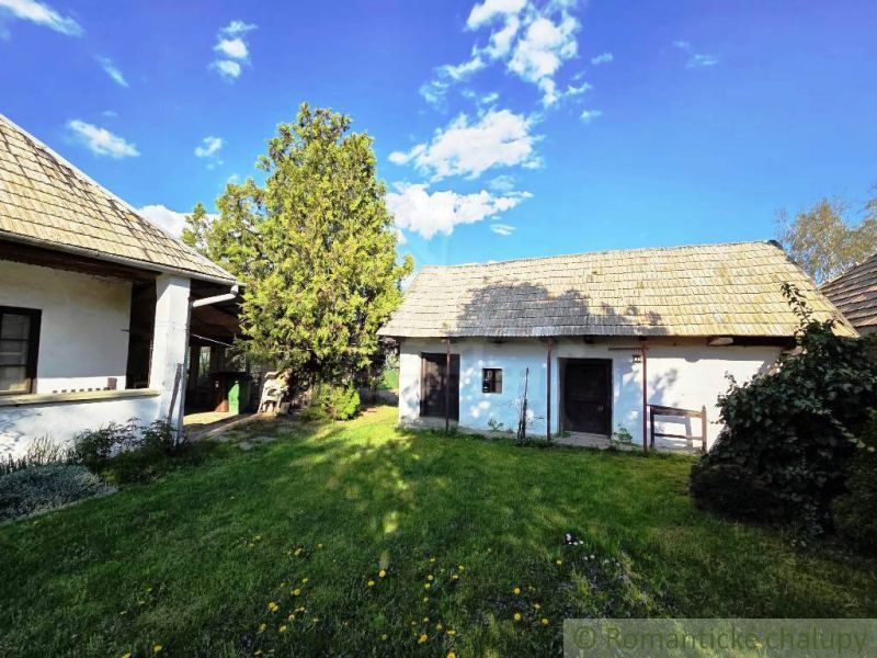 Two country cottages in Šahy with a grassy yard and trees.