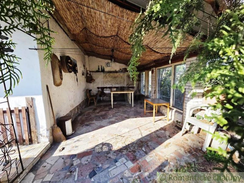 Covered terrace of the cottage in Šahy with a colorful stone floor and natural decorations.