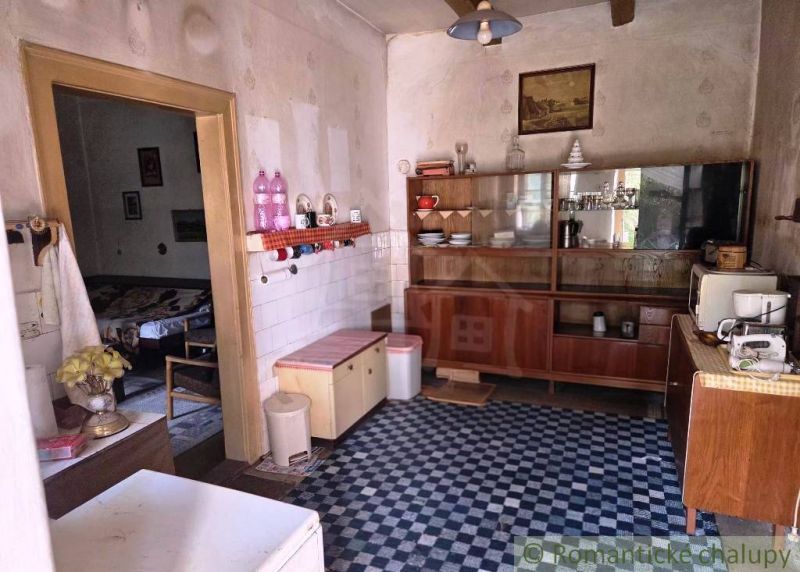 A cottage kitchen with retro furniture, tiles, and decorative elements.