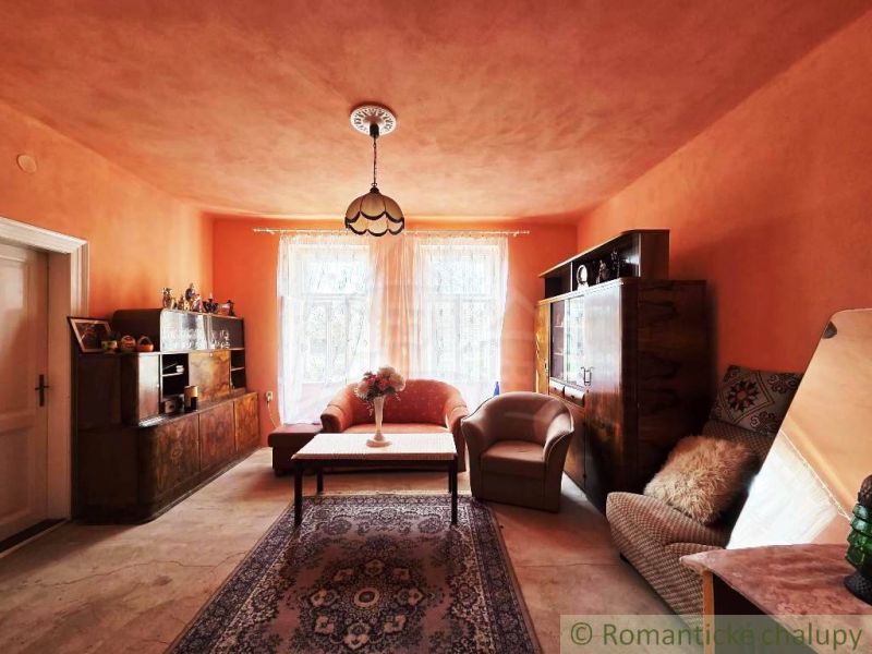 A living room in a family house with orange walls, a sofa, an armchair, and retro furniture.