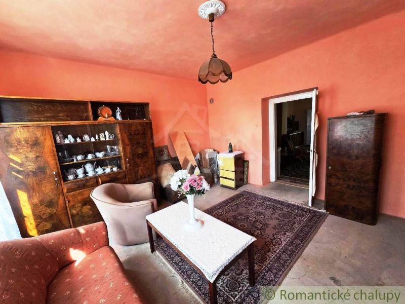 A living room in a family house with pink walls and wooden furniture.