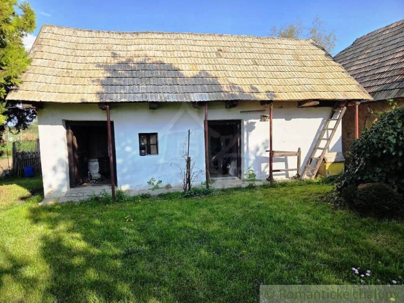 A cottage in Šahy with a thatched roof and a landscaped garden.