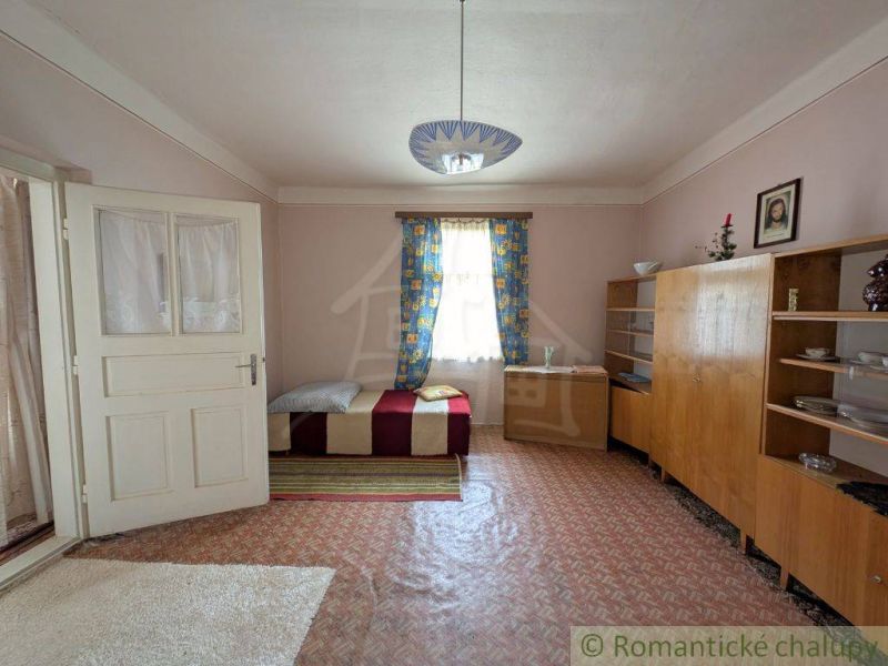 A room with simple furniture, a bed, and carpets in a family house.