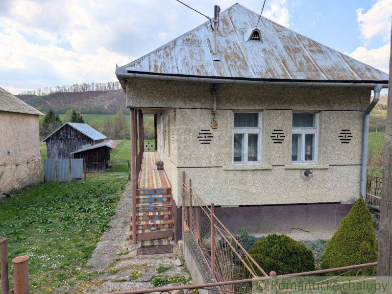 A family house in Zubné with a metal roof, a veranda, and surrounding lawn.