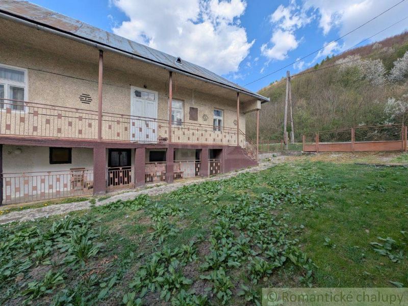 A family house in Zubné with a large veranda, green lawn, and slope.