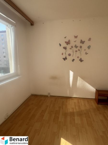 A room in a three-room apartment with a wooden decor floor and butterfly stickers on the wall.