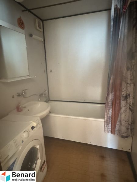 A bathroom in a 3-room apartment with a bathtub and a washing machine, bright tiles.