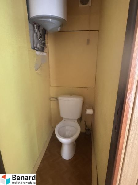 A bathroom in a 3-room apartment with a wooden decor floor and yellow walls.