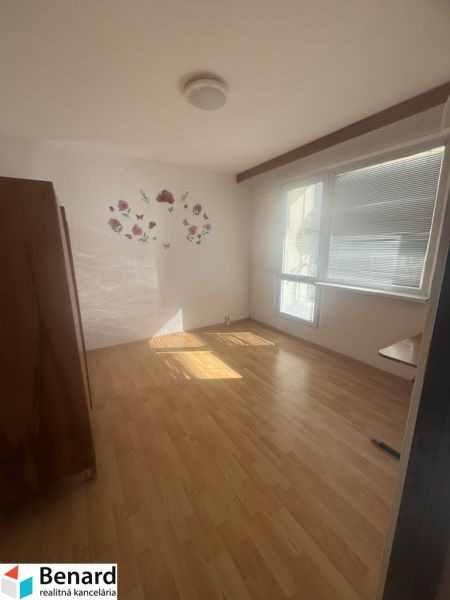 A room with a light wooden floor, a window, and light decoration on the wall.