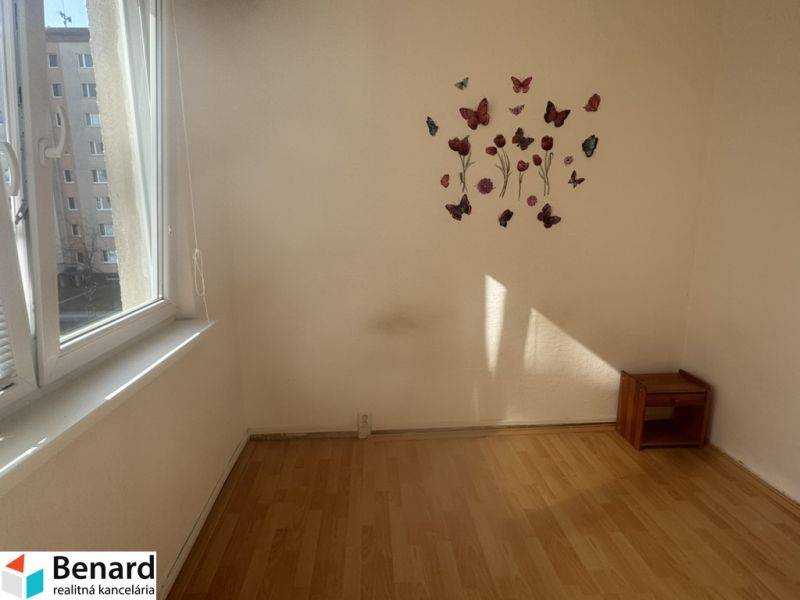 A room with a wooden decor floor, butterfly decorations, and furniture in a three-room apartment.