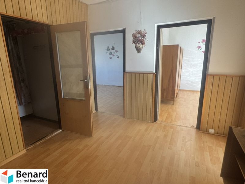 Interior of a 3-room apartment with a wooden decor floor, wooden paneling, and entrance doors.