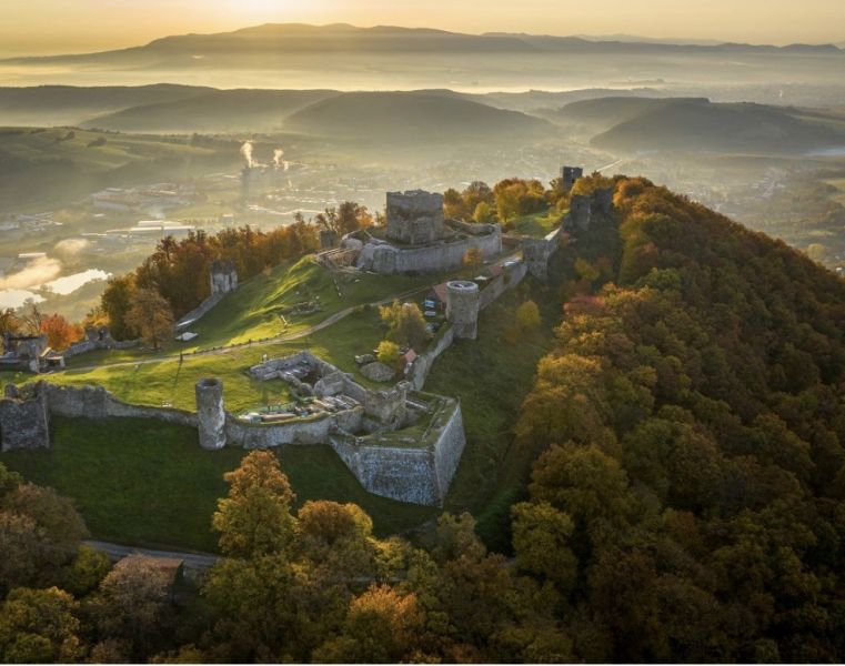 A castle on a hill surrounded by autumn-colored forests in the area of Veľký Šariš.
