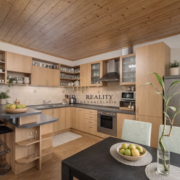 A kitchen in a family house with a wooden ceiling, a dining area, and modern equipment.