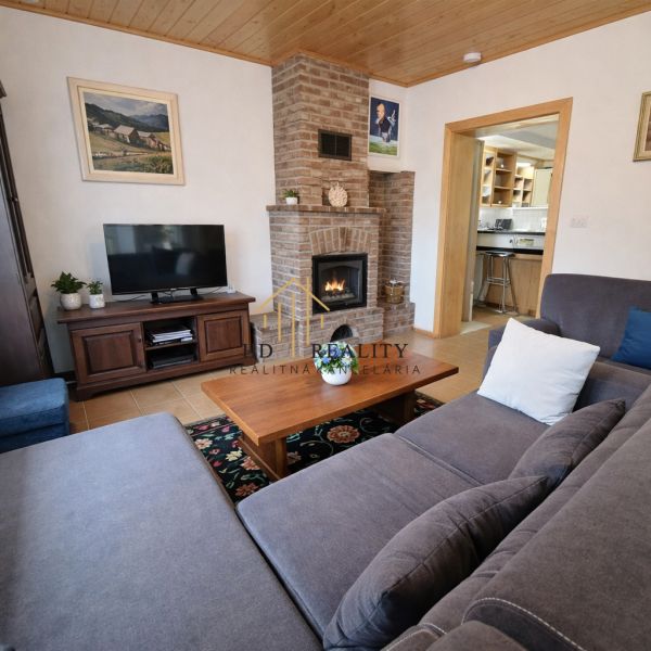 Living room with a fireplace and a sofa in a family house with a wood-patterned floor.