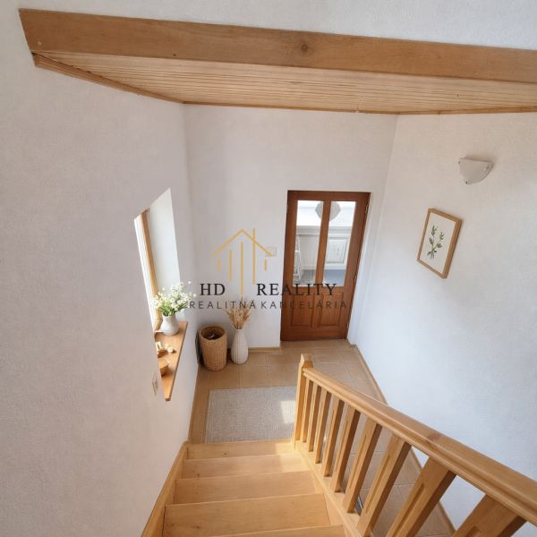 A family house with a staircase and wooden decor, flowers, and warm interior tones.