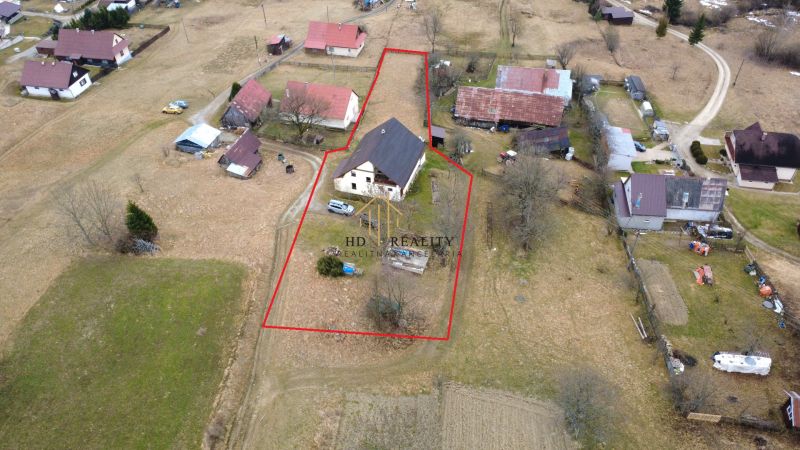 Aerial view of a family house in Oravská Lesná surrounded by land and neighboring buildings.