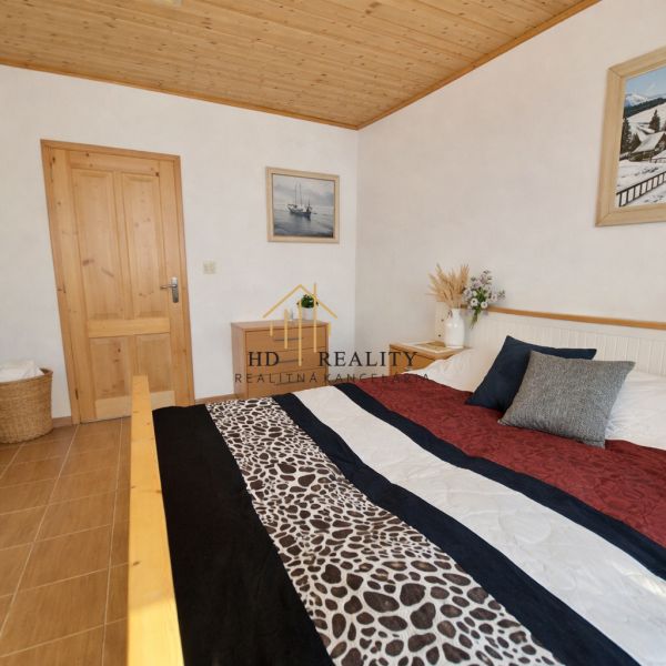 Bedroom in a family house with a wooden ceiling and a patterned bedspread.