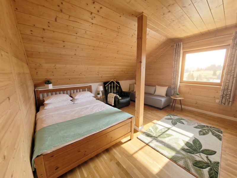 A bedroom in a family house with a bed, sofa, carpet, and wooden decor flooring.