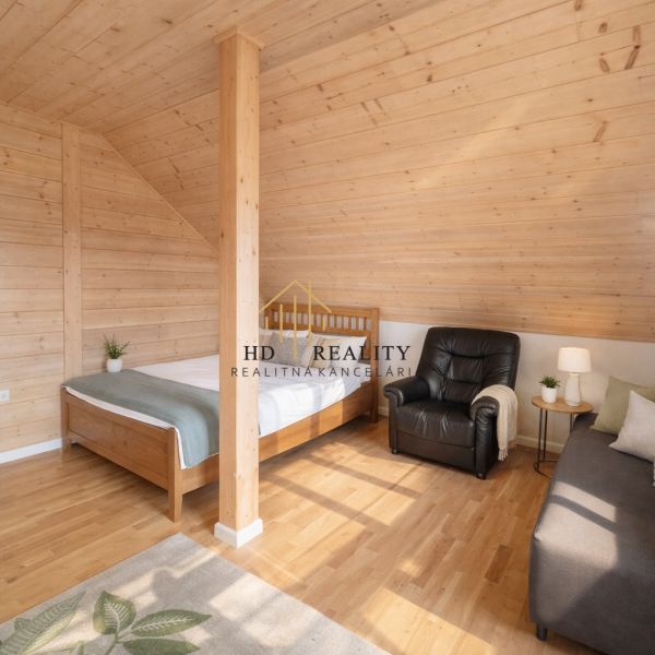 Attic room with a bed, chair, and wooden decor flooring in a family house.