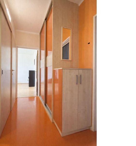 The hallway of a 3-room apartment with an orange floor and a built-in wardrobe.