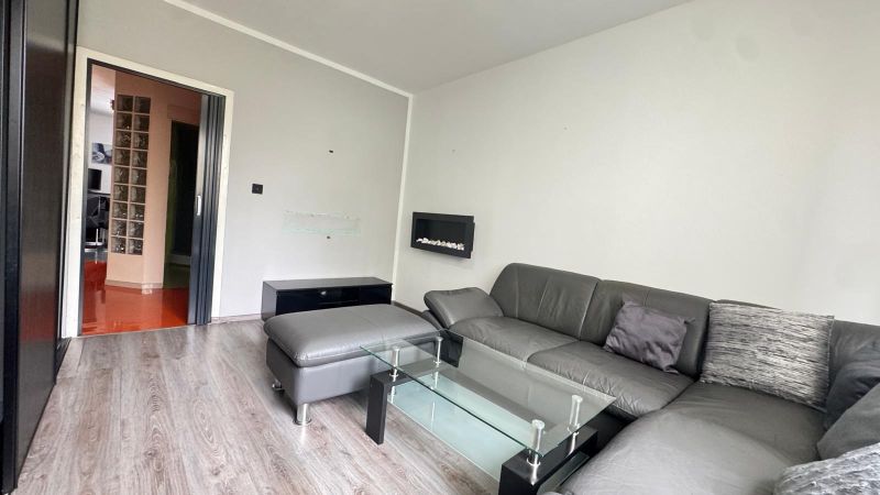 Living room in a 3-room apartment with a leather sofa and a wooden decor floor.