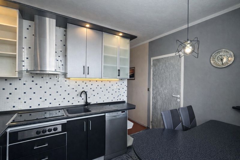 A kitchen in a 3-room apartment with tiles contrasting black and white elements.