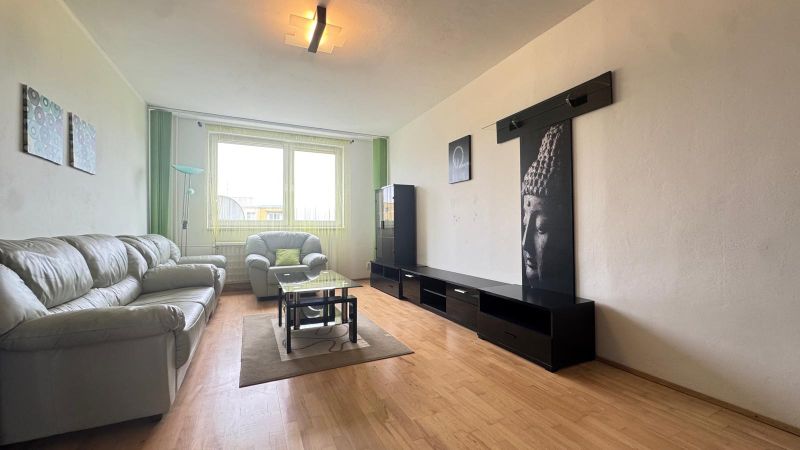 Living room in a 3-room apartment with a sofa, a glass table, and a wooden decor floor.