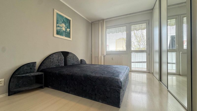 A bedroom with a large bed and a built-in wardrobe in a 3-room apartment.