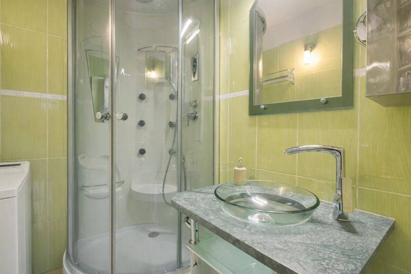A bathroom in a 3-room apartment with a shower and a glass sink.