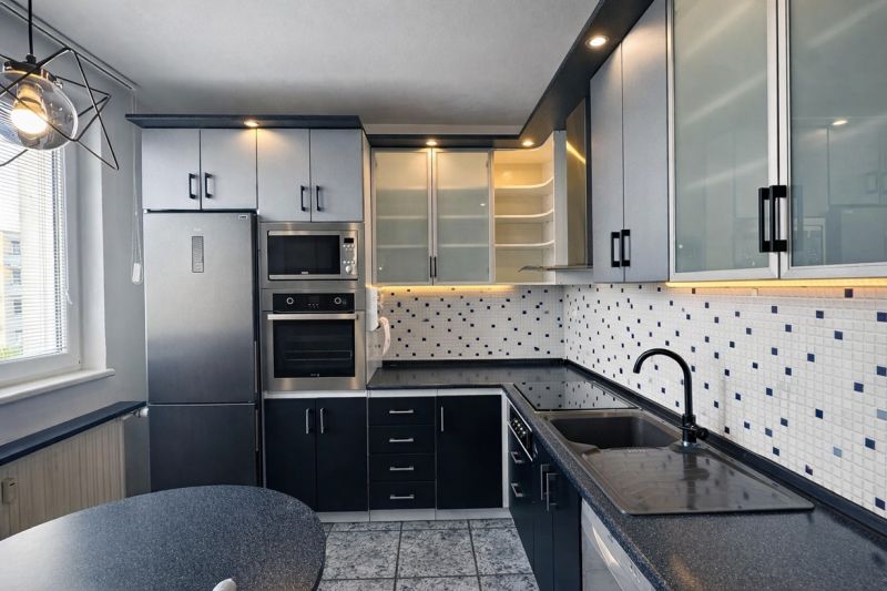 A kitchen in a 3-room apartment with ceramic tiles and spot lighting.