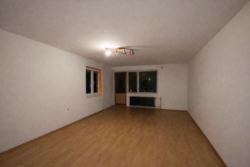 A spacious room in a family house with white walls and a wooden decor floor.