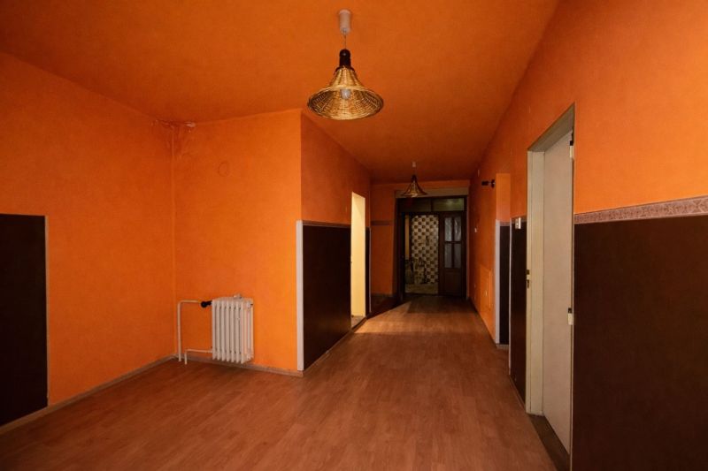 Orange hallway with wood-patterned flooring and ceiling lights in a family house.