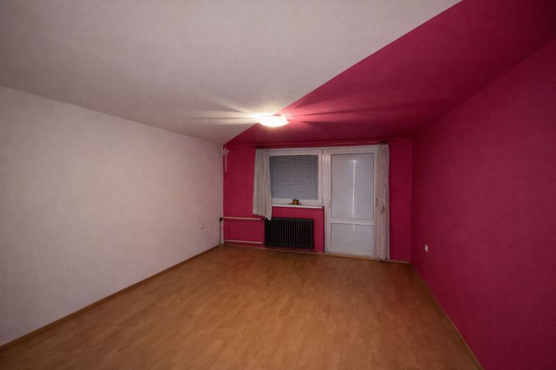 A room with pink walls and a wooden decor floor in a family house.