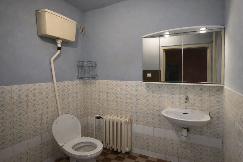 Bathroom with tiles, toilet, sink, and mirror in a family house.