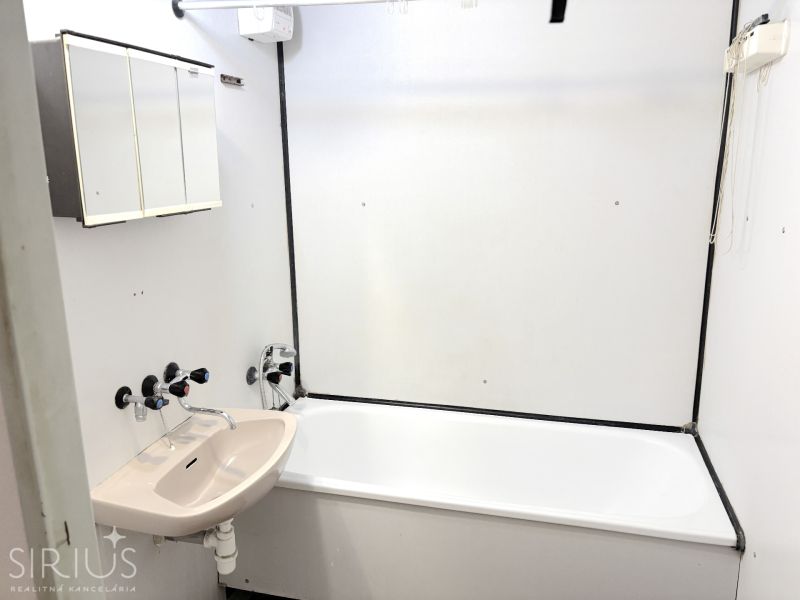 Bathroom with a bathtub and sink in a studio apartment.