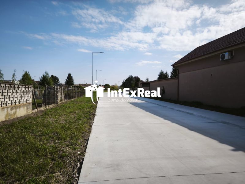 Concrete sidewalk in Čierny Brod for residential plots next to grassy and fenced areas.