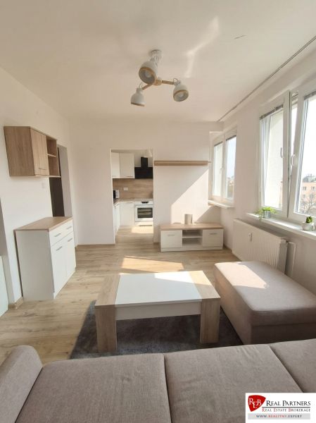 Interior of a 1-room apartment with light walls and a floor with a wood decor.