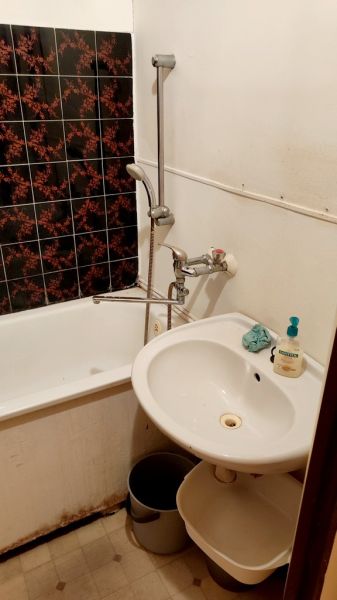 Bathroom with a bathtub, sink, and decorative tiles in a studio apartment.