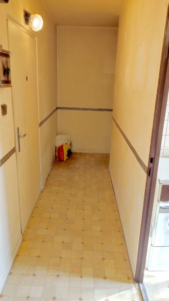 A narrow hallway in a one-room apartment with a tiled wall decor, light flooring.