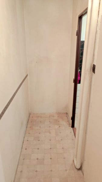 A narrow hallway in a studio apartment with white walls and patterned flooring.