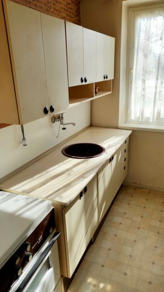 A kitchen in a one-room apartment with a simple kitchenette, built-in sink, and a window.