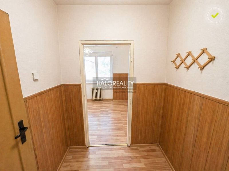 A narrow, lit basement with a window and wooden walls in a studio apartment.
