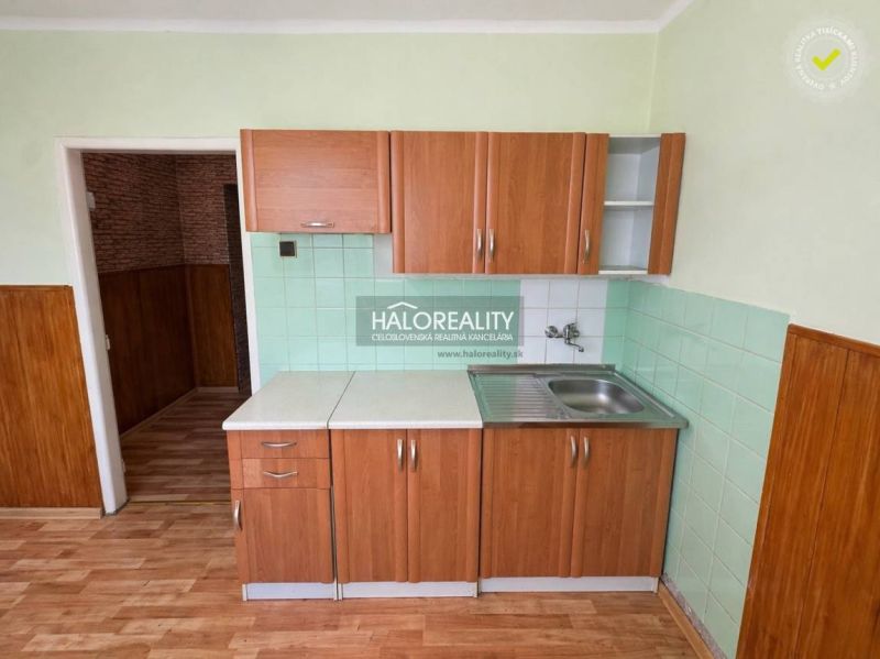 A kitchen in a studio apartment with tiles and wood-patterned flooring.