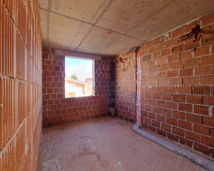 The interior of an unfinished 3-room apartment with brick walls and an opening for a window.