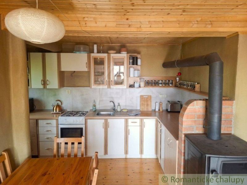 A kitchen in a family house with a rustic tiled stove and a wooden-patterned floor.